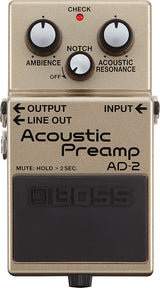 The image shows a Boss AD-2 Acoustic Preamp pedal for acoustic guitars. It features three control knobs: Ambience, Notch, and Acoustic Resonance. There is a red "CHECK" LED, labeled OUTPUT, INPUT, and LINE OUT jacks, and a large black footswitch with the Boss logo and "MUTE: HOLD > 2SEC" text. The pedal is champagne-colored and enhances acoustic tone with effects, feedback control, and resonance.