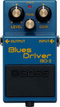 The image shows a Boss Blues Driver BD-2 guitar effects pedal, a popular overdrive/distortion pedal. It features three knobs (LEVEL, TONE, GAIN), a red "CHECK" LED, input/output jacks, and a blue housing with a black footswitch. Known for its warm, tube-like overdrive, the BD-2 is favored for blues, rock, and versatile guitar tones.