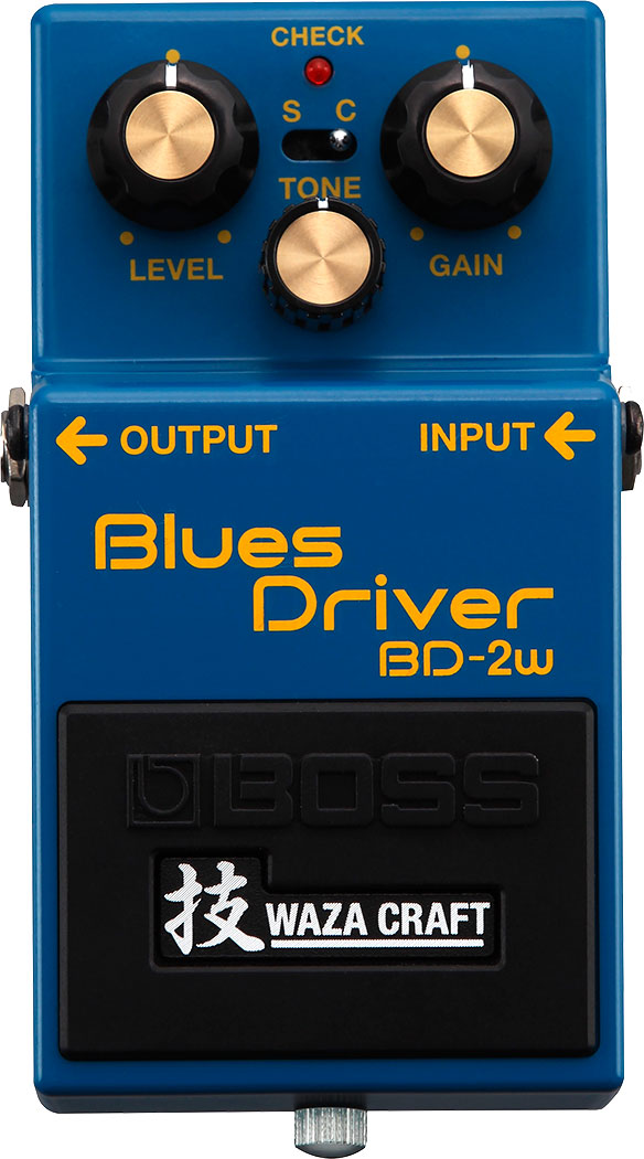 The image shows a Boss Blues Driver BD-2W guitar effects pedal, Waza Craft edition. It features LEVEL, TONE, and GAIN knobs, a CHECK light, and an S/C switch for Standard or Custom voicings. The blue compact pedal has INPUT/OUTPUT jacks, Boss branding, and Japanese "Waza" characters. The BD-2W offers classic and custom overdrive modes, delivering smooth, bluesy distortion favored across many music genres.