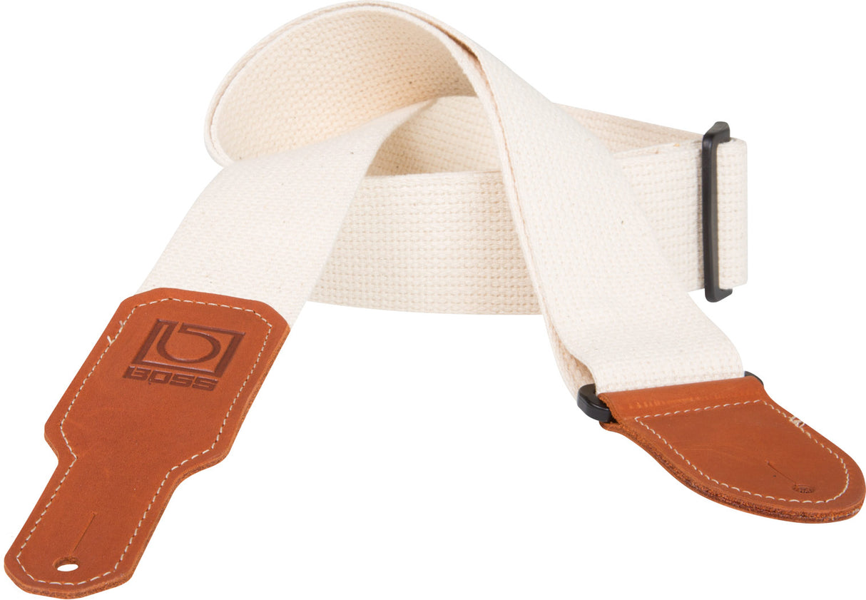 The image shows a guitar strap with cream/beige woven cotton webbing and brown leather ends featuring decorative stitching and the embossed BOSS logo. It has black plastic strap locks at both ends and an adjustable length for comfortable standing play. This durable, professional-grade strap supports the guitar’s weight, combining comfort and longevity for musicians.
