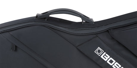 The image shows a black, soft-sided padded musical instrument gig bag with a sturdy top handle and multiple zippered compartments. It features reinforced stitching and the "BOSS" logo on the lower right corner. Designed for professional use, it likely protects electronic musical equipment such as keyboards or guitars, reflecting BOSS's reputation for electronic music gear. The sleek all-black design offers a protective and professional appearance.
