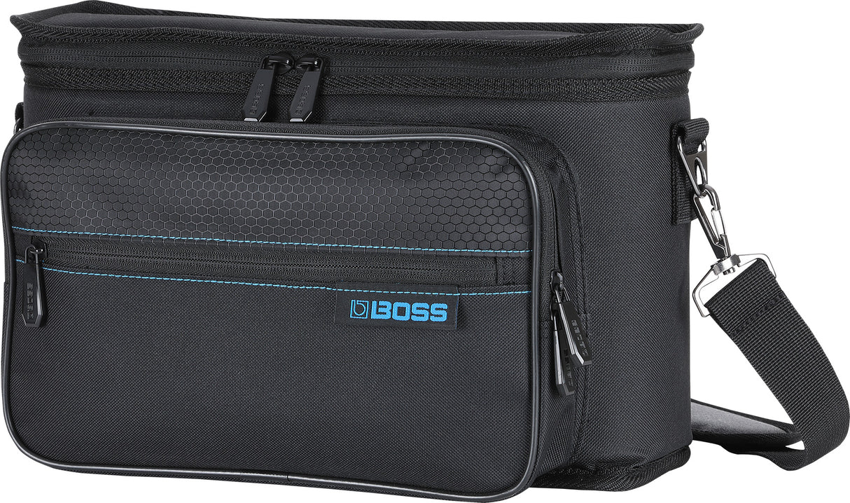 The image shows a black BOSS gig bag designed for transporting BOSS guitar effects pedals and small electronic music gear. It features the blue BOSS logo, multiple zippered compartments, a hexagonal textured front panel, blue accent stitching, and an adjustable shoulder strap. This professional bag helps musicians organize and protect their equipment for gigs, rehearsals, or studios.