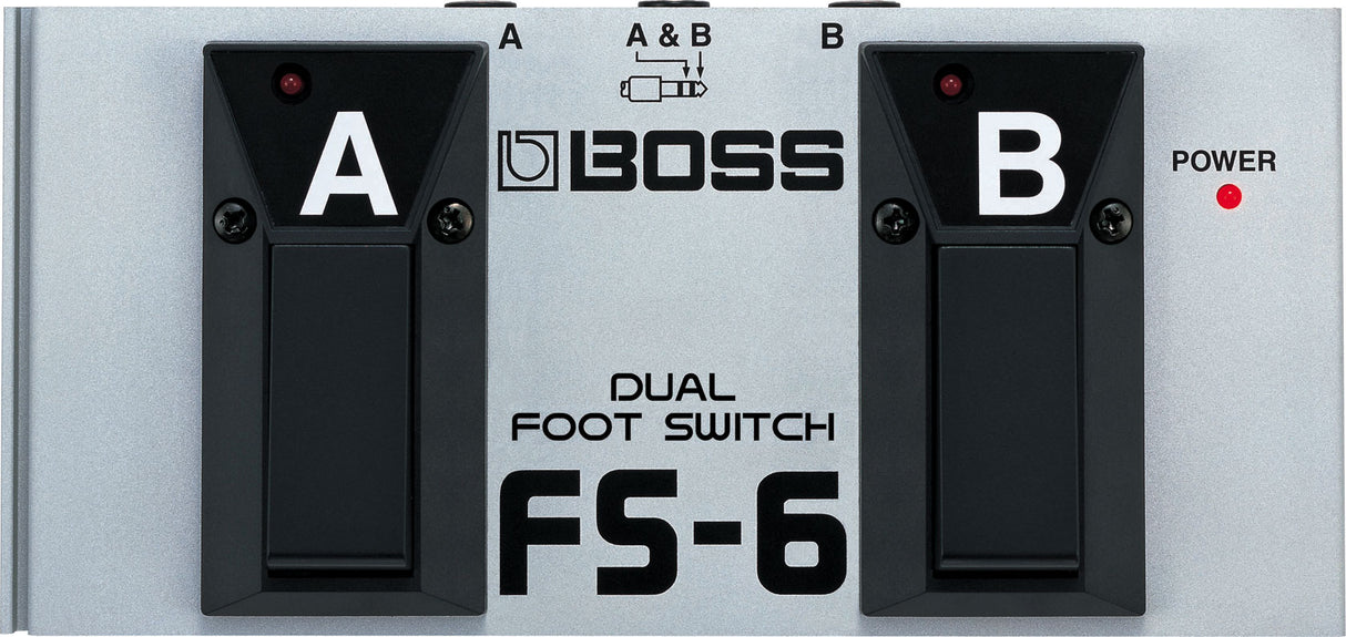 The image shows a Boss FS-6 Dual Foot Switch, a guitar accessory with two labeled foot switches (A and B), each with red LED indicators, and a power LED on the right. It features a metal body with black rubber pedals, the Boss logo in the center, and a top diagram showing switching options. Used by musicians to control amps or effects pedals hands-free during performance.