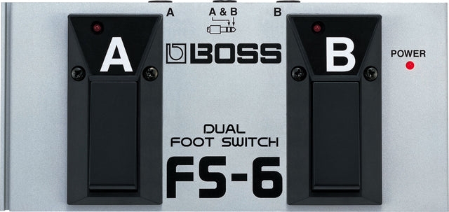 The image shows a Boss FS-6 Dual Foot Switch, a guitar accessory with two labeled foot switches (A and B), each with red LED indicators, and a power LED on the right. It features a metal body with black rubber pedals, the Boss logo in the center, and a top diagram showing switching options. Used by musicians to control amps or effects pedals hands-free during performance.