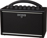 The image shows a BOSS Katana guitar amplifier by Roland, featuring a compact black design with the BOSS logo and Japanese katana symbol on the speaker grille. Visible are the control panel with knobs for gain, volume, EQ, and effects, a sturdy top handle for portability, and a protective speaker grille. This small, versatile amp is known for quality modeling and built-in effects, ideal for practice, recording, or small venues.