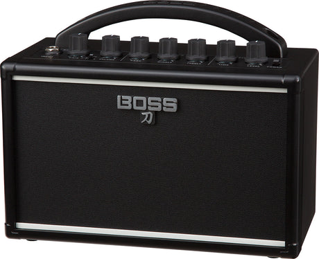 The image shows a BOSS Katana guitar amplifier by Roland, featuring a compact black design with the BOSS logo and Japanese katana symbol on the speaker grille. Visible are the control panel with knobs for gain, volume, EQ, and effects, a sturdy top handle for portability, and a protective speaker grille. This small, versatile amp is known for quality modeling and built-in effects, ideal for practice, recording, or small venues.