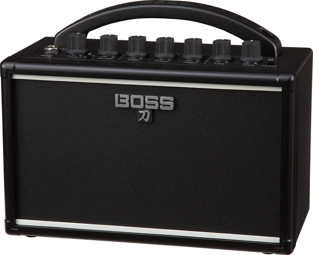 The image shows a BOSS Katana guitar amplifier by Roland, featuring a compact black design with the BOSS logo and Japanese katana symbol on the speaker grille. Visible are the control panel with knobs for gain, volume, EQ, and effects, a sturdy top handle for portability, and a protective speaker grille. This small, versatile amp is known for quality modeling and built-in effects, ideal for practice, recording, or small venues.
