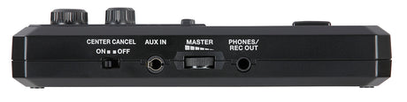 The image shows a compact, black audio effects pedal with two large knobs, a "CENTER CANCEL" switch, an "AUX IN" jack, a "MASTER" level knob, and a "PHONES/REC OUT" jack. White labels identify controls on its rectangular housing. It appears to be a vocal or karaoke processor designed to reduce lead vocals and support practice, recording, or performance with various audio sources.
