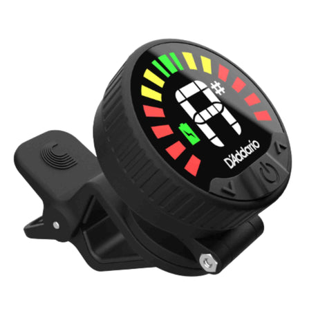 The image shows a D'Addario clip-on chromatic guitar tuner with a circular display featuring colorful LED indicators and "G#" note detected. It has a black plastic housing with the brand name, a spring-loaded clip for attaching to a guitar headstock, and side buttons for power and mode. The tuner displays pitch feedback using green, yellow, and red bars and picks up vibrations directly from the instrument.