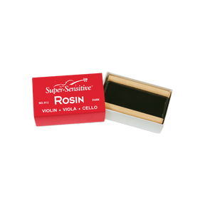 The image shows a block of "Super-Sensitive ROSIN" for violin, viola, and cello, labeled as the dark variety (No. 912). The rosin, dark amber or black in color, is housed in a small wooden or cardboard holder inside a red and white box. Rosin is essential for string instruments, applied to bow hair to create friction needed for sound when playing with a bow.
