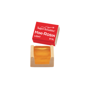 The image shows a Super-Sensitive Mini-Rosin for string instruments, a small rosin cake in a cardboard box with a red label. The rosin is light amber and labeled "LIGHT 913L." Rosin is used on bow hairs to create friction for sound production. This compact size is ideal for students or musicians needing a portable option. Super-Sensitive is a trusted brand for string players.