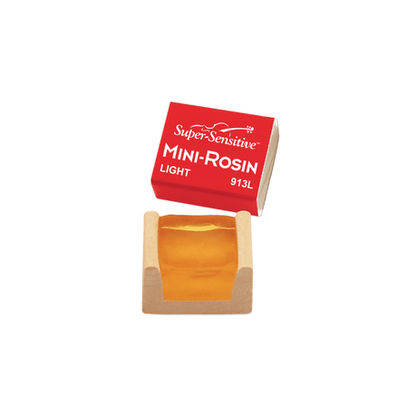 The image shows a Super-Sensitive Mini-Rosin for string instruments, a small rosin cake in a cardboard box with a red label. The rosin is light amber and labeled "LIGHT 913L." Rosin is used on bow hairs to create friction for sound production. This compact size is ideal for students or musicians needing a portable option. Super-Sensitive is a trusted brand for string players.