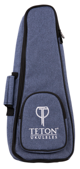 The image shows a Teton TBS25BL soprano ukulele gig bag in black. The bag features a zippered front pocket, padded shoulder straps, and a top handle for easy carrying. Its compact design is tailored to fit a soprano ukulele securely, providing protection during transport. The Teton logo is visible on the front pocket. The background is plain and the bag is displayed upright.