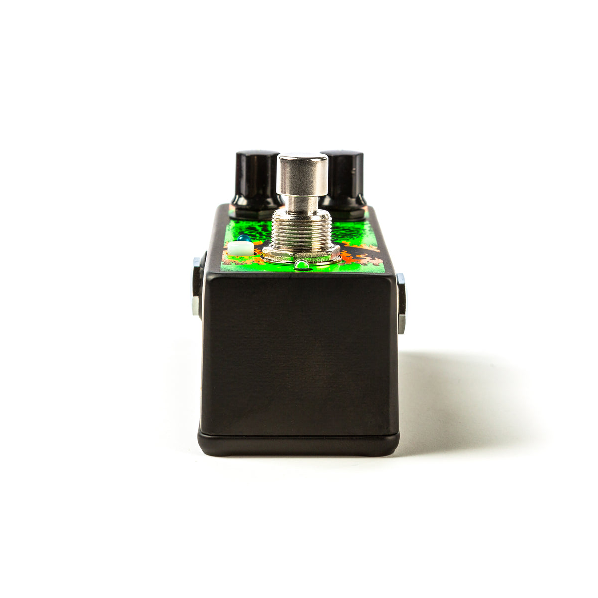 The bottom of a Jimi Hendrix guitar pedal with the footswitch visible along with the black finished bottom.