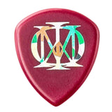 The image shows a classic teardrop-shaped guitar pick with a red/maroon plastic base. It features a colorful, artistic monogram or brand logo in the center with white, green, and orange elements. The pick appears to be medium thickness, suitable for general playing, and may be a branded or collectible accessory used to strum or pluck guitar strings.