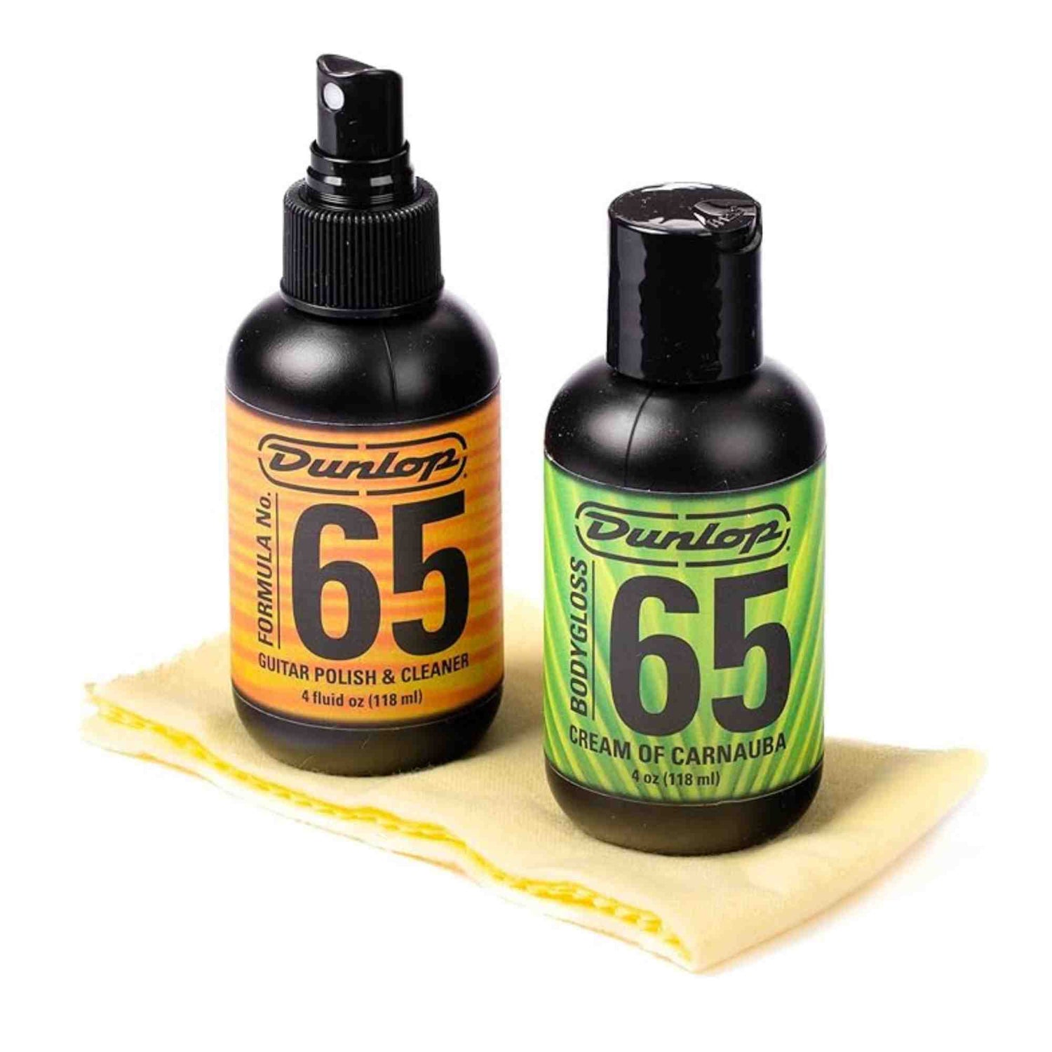 The image shows two Dunlop Formula 65 guitar care products: a 4 oz black spray bottle of Guitar Polish & Cleaner with an orange label, and a 4 oz black flip-top bottle of Cream of Carnauba with a green label. A yellow textured polishing cloth is also included. These products are used to clean, polish, and protect guitar finishes, helping maintain the instrument’s appearance and condition.