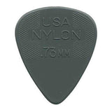 The image shows a gray nylon guitar pick with "USA NYLON .73MM" embossed on it, indicating its origin, material, and thickness. It has a classic teardrop shape with textured crosshatch grips on both sides near the wide end to prevent slipping. At .73mm thickness, it offers a balanced feel suitable for strumming and precise picking. This common pick is used by guitarists of all levels across genres.