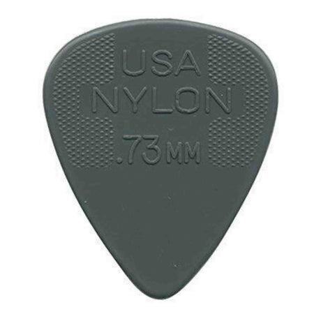 The image shows a gray nylon guitar pick with "USA NYLON .73MM" embossed on it, indicating its origin, material, and thickness. It has a classic teardrop shape with textured crosshatch grips on both sides near the wide end to prevent slipping. At .73mm thickness, it offers a balanced feel suitable for strumming and precise picking. This common pick is used by guitarists of all levels across genres.