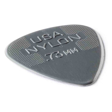 The image shows a Dunlop Nylon guitar pick in dark gray/black with a thickness of 0.73mm. It features the classic teardrop shape and textured crosshatched grip areas on the upper part to prevent slipping. This medium gauge pick is popular for its durability and balanced flexibility, suitable for both strumming and detailed picking.