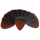 The image shows a collection of D'Addario guitar picks with "SCULPTED" and "PLECTRA" branding. The picks have a two-tone design, combining reddish-brown and dark colors, and feature smooth and textured grip surfaces. They are arranged fan-like, including standard teardrop and smaller, pointed jazz picks, offering a variety of shapes and textures suited for different playing styles and techniques.