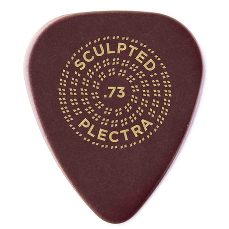 The image shows a "Sculpted Plectra" guitar pick with a .73mm medium gauge thickness. It features a dark reddish-brown tortoiseshell-style material and an intricate circular pattern of small square perforations for grip. Gold-yellow text and decorative elements enhance its premium look. This boutique pick combines aesthetic detail with functional design, suitable for versatile playing styles from strumming to picking.
