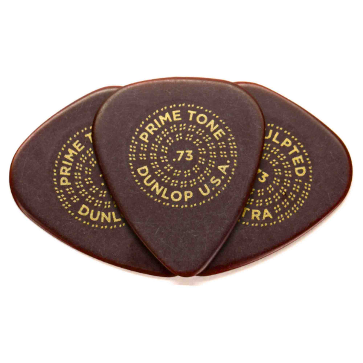 The image shows three dark brown or tortoiseshell Dunlop Primetone guitar picks with gold lettering. Each pick features "PRIME TONE," "DUNLOP U.S.A," and the number "73" (0.73mm thickness) arranged in a circular pattern. These premium teardrop-shaped picks are made from Primetone material, known for its smooth feel, warm tone, durability, and a textured grip area favored by acoustic and electric guitar players.
