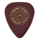 The image shows a Dunlop USA Primetone guitar pick with a .73mm thickness, printed in gold on its dark reddish-brown teardrop-shaped surface. Known for smooth play and durability, this medium-gauge pick features a decorative circular dot pattern around the text, adding visual appeal and extra grip for strumming or picking guitar strings.