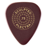 The image shows a deep red Sculpted Plectra guitar pick with a gold circular design. The circle features "SCULPTED" at the top, "PLECTRA" at the bottom, and ".73" in the center, indicating thickness in millimeters. Decorative dotted concentric circles surround the text. The premium pick’s elegant design and likely sculpted shape suggest enhanced grip and tone, suitable for various playing styles.