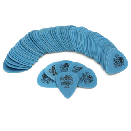 The image shows a large collection of blue Dunlop guitar picks arranged in a curved, fan-like pattern. Several picks are displayed in front, clearly showing the Dunlop logo and text. The picks are a consistent blue/teal color and appear to be medium gauge, commonly used by guitarists. This typical product photo highlights essential guitar accessories.