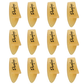 The image shows 12 Dunlop guitar picks arranged in a 3x4 grid. Each pick features the Dunlop logo and an "M," indicating medium thickness. They have a classic teardrop shape with pointed tips and are made of translucent amber-colored material, likely celluloid. These picks are popular guitar accessories used for strumming and picking, known for quality and precision.