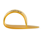The image shows a translucent amber guitar thumb pick with a curved, wraparound design that fits over the thumb and extends a flat picking surface outward. Some branding is visible on the band. Thumb picks like this are used by fingerstyle guitarists and banjo players to produce a brighter bass sound while allowing finger play on higher strings, popular in bluegrass, country, and folk music.