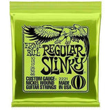 The image shows a package of Ernie Ball Regular Slinky electric guitar strings, model 2221, with bright green packaging and the eagle logo. It contains nickel-wound strings in the 10-46 gauge set (10, 13, 17, 26, 36, 46). This popular set offers a balanced tone and playability, favored by guitarists across genres. Ernie Ball is a trusted brand known for quality guitar strings.