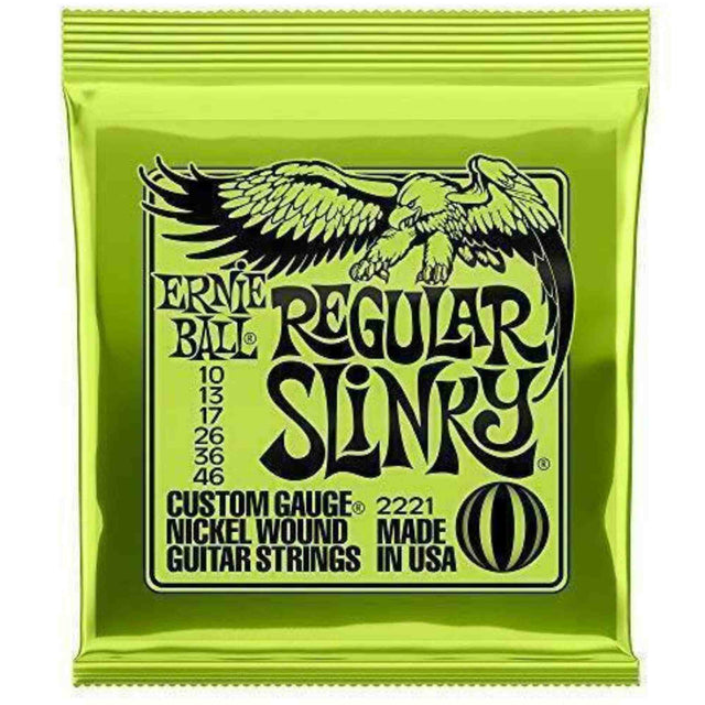 The image shows a package of Ernie Ball Regular Slinky electric guitar strings, model 2221, with bright green packaging and the eagle logo. It contains nickel-wound strings in the 10-46 gauge set (10, 13, 17, 26, 36, 46). This popular set offers a balanced tone and playability, favored by guitarists across genres. Ernie Ball is a trusted brand known for quality guitar strings.