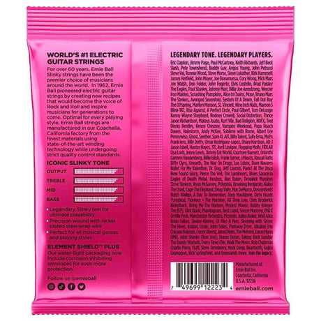The image shows a package of Ernie Ball electric guitar strings from the popular "Slinky" series. The bright pink box highlights features like nickel-plated steel strings, Element Shield Plus corrosion protection, and the "Iconic Slinky Tone" with frequency charts. It also displays endorsements from legendary guitarists like Eric Clapton, Jimmy Page, and Slash. Made in Coachella, California, these strings offer legendary feel and sound for all styles.