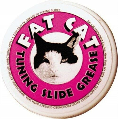 The image shows a container of Fat Cat Tuning Slide Grease, a lubricant for brass wind instruments. It has a pink label with a black and white cat face. This grease is applied to tuning slides—the U-shaped parts on brass instruments like trumpets and trombones—to keep them moving smoothly, aiding in pitch adjustment and preventing them from sticking.