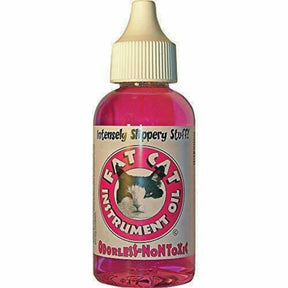 The image shows a bottle of Fat Cat Instrument Oil, "Intensely Slippery Stuff" formula. The label features a red circular badge with a cat logo and the text "FAT CAT INSTRUMENT OIL," "Intensely Slippery Stuff" at the top, and "ODORLESS-NONTOXIC" at the bottom. This odorless, non-toxic lubricating oil in a dropper bottle is used for maintaining and lubricating parts of wind and other musical instruments.
