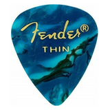 The image shows a Fender guitar pick with a blue marbled, ocean wave pattern. It features the gold Fender logo and "THIN" indicating its thickness. The swirling blue and teal design has darker veins, resembling natural stone or waves. This thin pick offers flexibility and a softer string attack, popular among rhythm guitarists. Fender picks are well-known for their quality and variety in the music industry.
