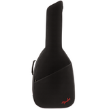 The image shows a black Fender guitar gig bag made of durable fabric with padding for protection. It has the classic guitar shape suitable for acoustic or electric guitars, a carrying handle, and a front pocket for accessories. The red Fender logo is visible at the bottom right. This soft-sided case is lightweight and popular among guitarists for easy transport and storage.