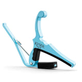 The image shows a bright turquoise Kyser guitar capo with a spring-loaded, quick-change design. This popular Quick-Change model features padded contact points to protect the guitar, durable construction, and easy one-handed clamping. Kyser is a trusted brand, and this capo allows guitarists to quickly change keys by clamping across the fretboard without altering chord fingerings.