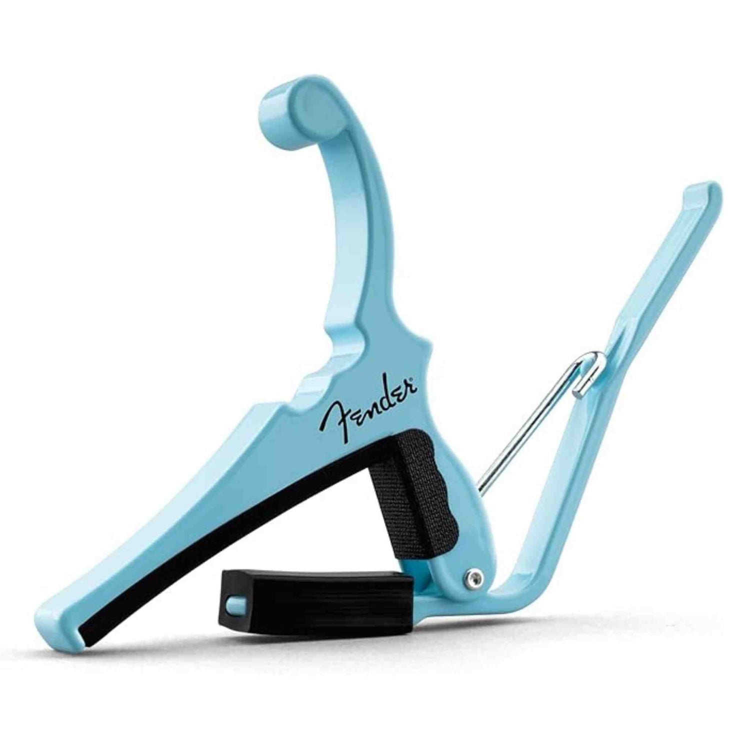 The image shows a Fender guitar capo in light blue/turquoise with the Fender logo. It features a spring-loaded design for one-handed use, black rubber padding to protect the guitar, and a hinged arm for even pressure across strings. This essential accessory lets guitarists easily change keys while using familiar chords, popular across many genres from folk to rock.