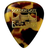 The image shows a tortoiseshell-patterned guitar pick with brown, amber, and dark mottled colors. It features gold text reading "GOLDEN GATE" and an illustration of the Golden Gate Bridge, suggesting a San Francisco-themed souvenir. This pick is a common accessory for string instrument players, with a classic design originally inspired by real tortoiseshell but now made from synthetic materials.
