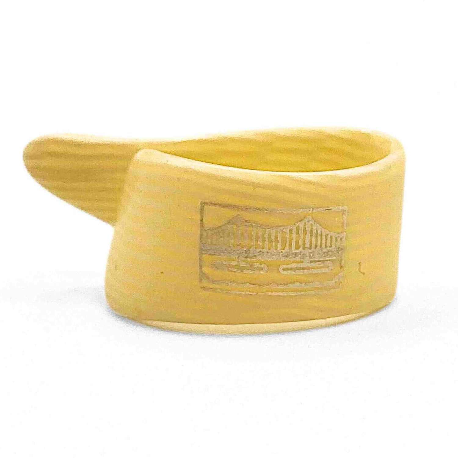 The image shows a saxophone mouthpiece made of a light-colored, yellowish-amber material, likely hard rubber or plastic. It features the typical curved shape with a chamber opening and has embossed manufacturer markings or a logo on the side. This essential component attaches the reed and is where the musician places their mouth, significantly influencing the instrument’s tone and playability.