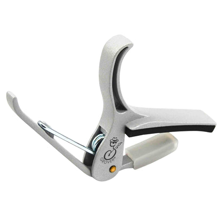 The image shows a Grover spring-loaded trigger-style guitar capo with a silver/chrome finish. It features a curved clamp, padded contact points to protect the guitar neck and strings, and a spring trigger for easy one-handed use. This professional-grade capo raises the pitch of all strings simultaneously, allowing guitarists to change keys without new fingerings, suitable for both acoustic and electric guitars.