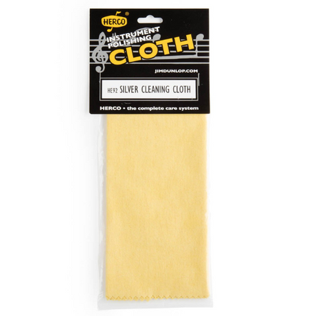 The image shows a Herco HE92 Silver Cleaning Cloth in light yellow/cream microfiber, designed for polishing silver musical instruments. It is packaged with a black header card featuring the Herco logo and "Instrument Polishing Cloth" branding. This cloth is used to clean and maintain brass and silver wind instruments, helping remove tarnish as part of Herco's complete care system.