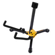 The image shows a tripod-style guitar stand with a black metal frame and a yellow-orange central hub. It has three foldable legs with protective caps for stability and floor protection, plus a padded vertical support to cradle a guitar neck. Designed to safely hold acoustic or electric guitars, it keeps instruments accessible and secure while being portable for transport to gigs or rehearsals.