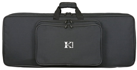 The image shows a black Kaces keyboard gig bag with the logo in white on the front. It has a padded, comfort-grip handle, multiple zippered compartments including a main keyboard section and front pocket, and black hardware. The large, rectangular soft case is designed for transporting full-size keyboards (61-88 keys) and offers a sleek, professional look for musicians on the go.