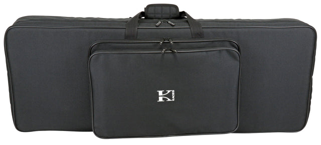 The image shows a black soft-sided keyboard gig bag with padded protection, multiple carrying handles, and several zippered compartments for an electronic keyboard or digital piano. It features a white "K" logo, likely from the Kaces brand, and includes storage pockets for accessories, making it lightweight and portable for musicians transporting their instruments and gear.