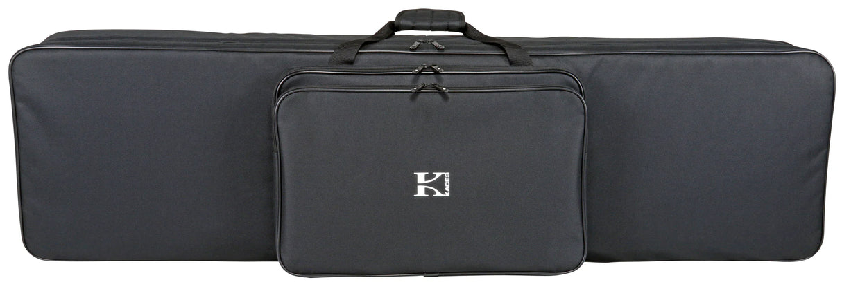 The image shows a Korg soft-shell keyboard gig bag in black fabric with a "K" logo on the front zippered pocket. It features a large main compartment for a keyboard, top carry handles, and a long rectangular shape. Designed for easy transport, it protects electronic keyboards from dust, moisture, and minor impacts while storing accessories like cables and pedals in the front pocket.