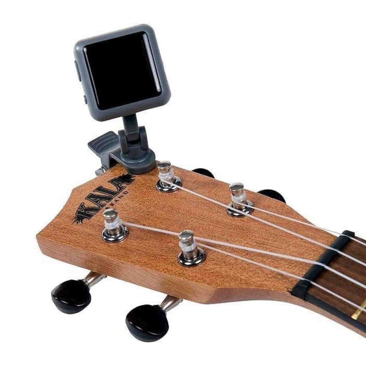 The image shows a wooden Kala ukulele headstock with four black tuning pegs and strings. Attached is a clip-on electronic tuner with a black screen and dark body, used to detect vibrations for accurate tuning. This setup is common for ukulele players, offering convenient, cable-free tuning for acoustic instruments.