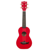 The image shows a bright red Makala soprano ukulele with a dark fretboard featuring dot markers, four strings, six tuning pegs with light-colored buttons, and a black bridge with a decorative shark design. The "MAKALA" logo is visible on the headstock. This small, traditional ukulele is popular among beginners for its affordability and vibrant, eye-catching appearance.